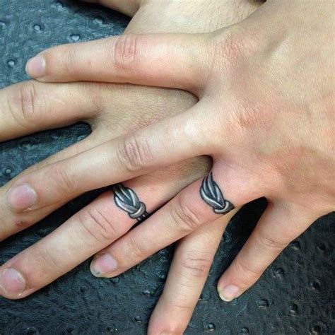 Two Peoples Hands With Tattoos On Them One Has A Ring And The Other