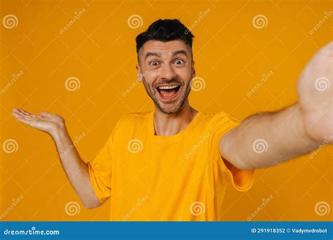 Cheerful Man Taking Selfie On Mobile Phone And Holding Copy Space Isolated Over Yellow Wall