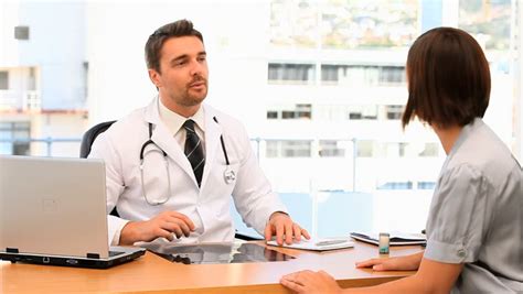 Doctor Asking Questions To His Patient In The Medical Office Stock
