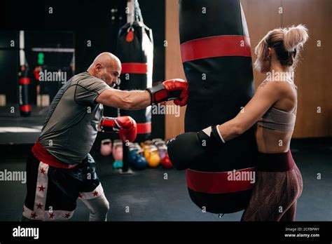 Side View Of Strong Female Athlete In Boxing Gloves Holding Punching