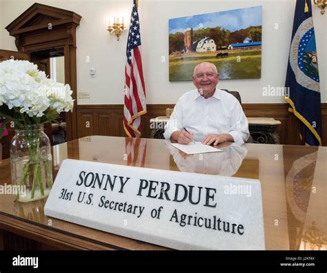 Us Agriculture Secretary Sonny Perdue Smiles As He Sits Behind His
