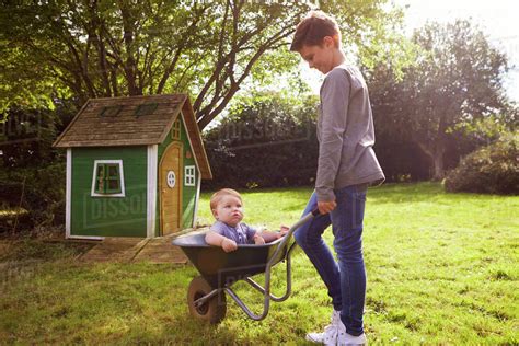 Boy Pushing Baby Brother In Garden Wheelbarrow Stock Photo Dissolve
