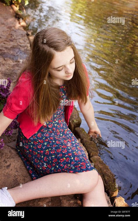 Beautiful Teenage Girl Sitting Beside A River And Dipping Her Hands