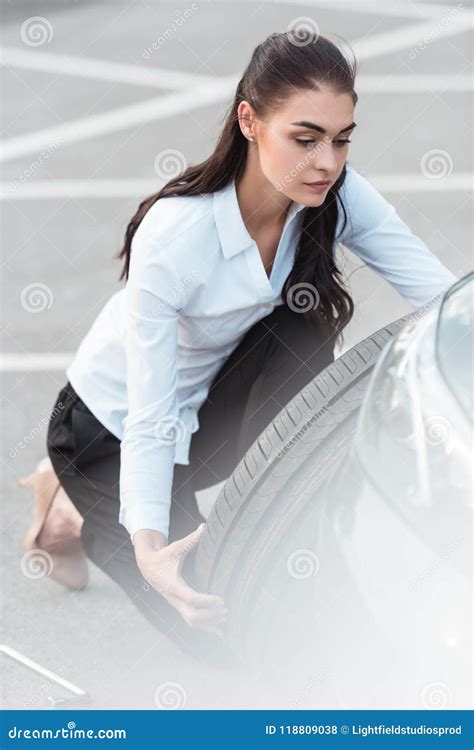 Young Attractive Woman In Formal Wear Holding A Spare Car Tire Stock
