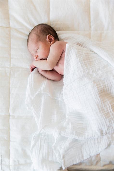 Overhead View Of Tiny Infant Sleeping On White Bedding By Stocksy