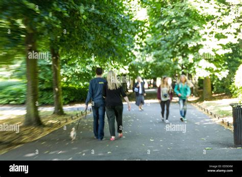 People Strolling Through A Park On A Summers Day Blurry In Parts Stock