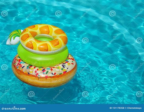 Stack Of Colorful Inflatable Rings Floating In Swimming Pool On Sunny