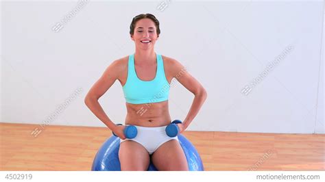Fit Brunette Sitting On An Exercise Ball And Lifti Stock Video Footage