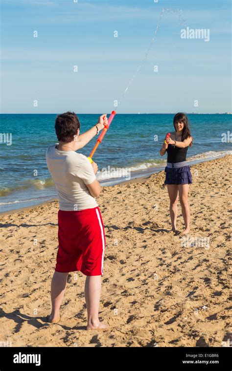 Couple Having Fun On The Beach With Squirt Guns Stock Photo Alamy