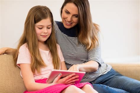 free photo mother and daughter using digital tablet in living room