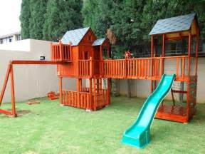 A Wooden Play Set With A Slide And Climbing Frame In The Grass Next To