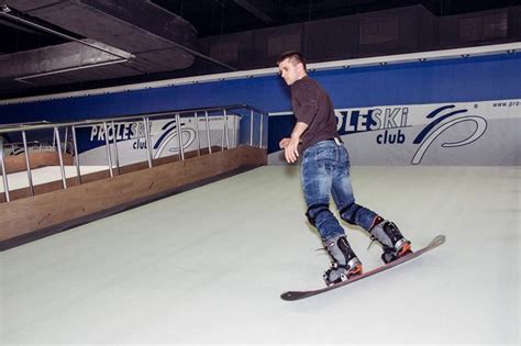 A Man Riding A Skateboard Down The Side Of A Snow Covered Slope In An Indoor Skating Rink