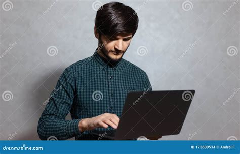 Portrait Of Young Man Holding Laptop Typing On Keyboard Looking At
