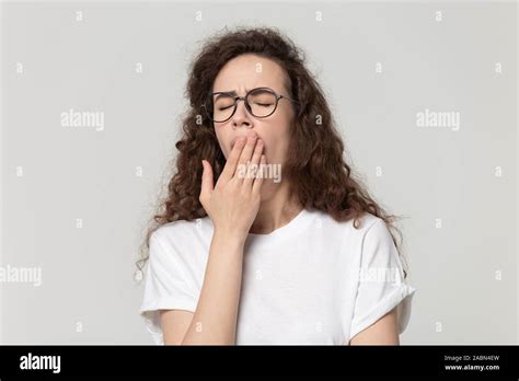 Exhausted Millennial Girl In Glasses Yawn Covering Mouth Stock Photo