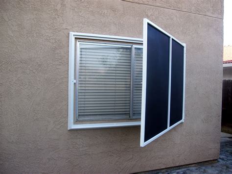 An Open Window On The Side Of A Tan Colored Building With Shutters And