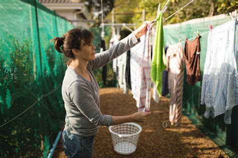 Senior Woman Hanging Laundry On Clothes Line On A Sunny Day Stock Photo