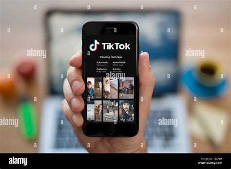 A Man Looks At His Iphone Which Displays The Tik Tok Logo Editorial