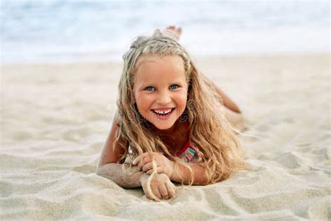 entzückendes kleines blondes mädchen entspannen sich auf sandigem strand genießen meer stockfoto