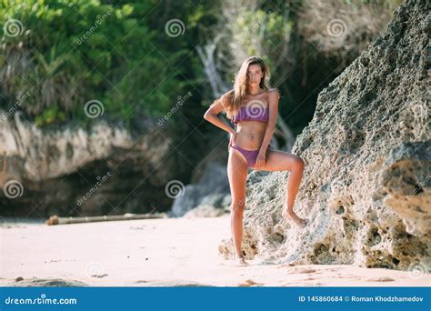 Slender Tanned Girl In Swimsuit Posing On Beach With Sand And Large