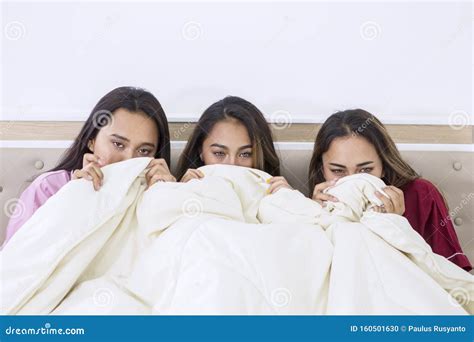 Scared Teenage Girls Watching A Horror Movie In Bed Foto De Stock