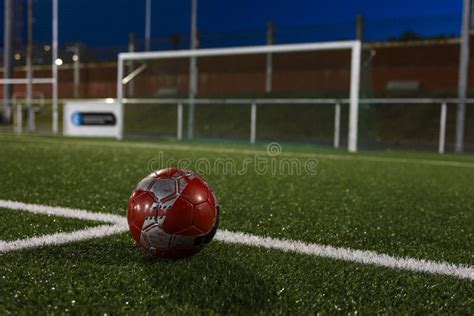 A Red Soccer Ball Is Crossing The White Lines Of The Football Field