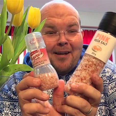 The Man Is Holding Two Bottles Of Spices In Front Of Flowers And Tulips
