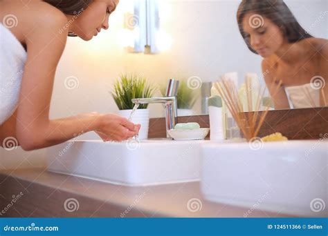Young Woman Washing Her Face With Clean Water In Bathroom Stock Photo
