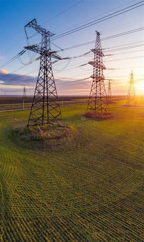 High Voltage Lines And Power Pylons In A Green Agricultural Field