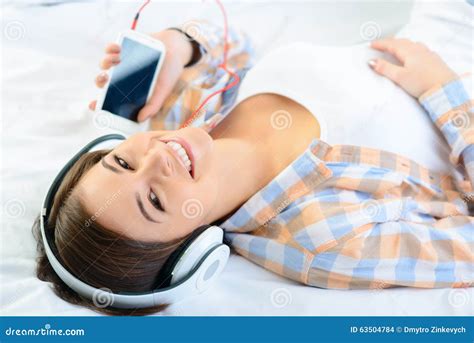 Positive Girl Lying In Bed And Listening To Music Stock Photo Image