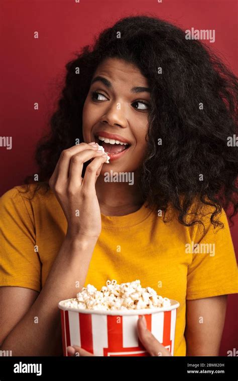 image of beautiful brunette african american woman with curly hair smiling and holding popcorn