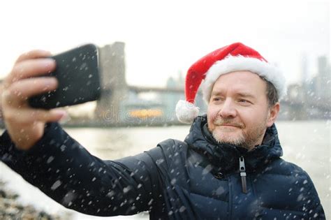 Local Man In Santa Claus Hat Takes Selfie In Front Of View Of Brooklyn