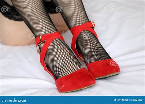 Female Legs In Black Fishnet Stockings And Red Shoes On High Heels