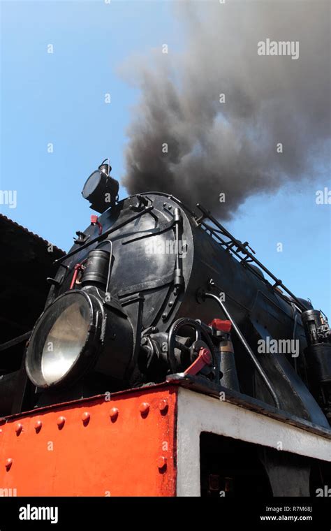 Detail Of Vintage Steam Engine With Smoke Against Blue Sky Stock Photo