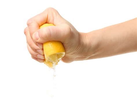 Female Hand Squeezing Half Of Lemon On White Background Lindsey Elmore