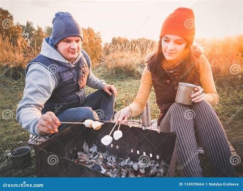 Happy Smiling Couple Roasting Marshmallows On Campfire On Nature