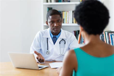 African American Doctor Explaining Diagnosis To Female Patient Stock
