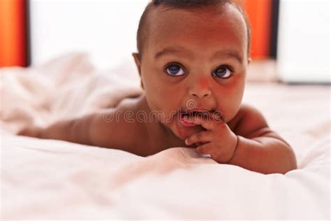 African American Baby Lying On Bed Having Legs Massage At Home Stock
