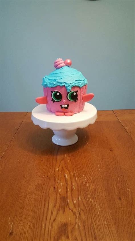 A Pink Cupcake With Blue Frosting On Top Of A White Cake Platter