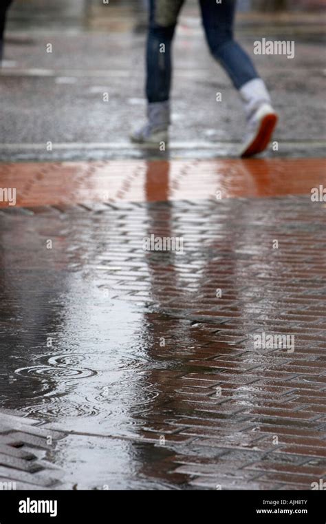 Rain Dripping Drops Into A Puddle Of Water In Pedestrian Area Of City