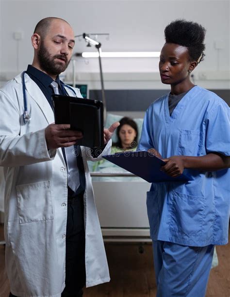 Doctor Reading Lab Results From Digital Tablet To Nurse Holding