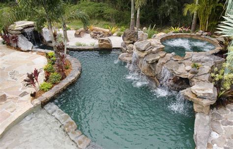 An Outdoor Swimming Pool With Rocks And Water Features Surrounded By