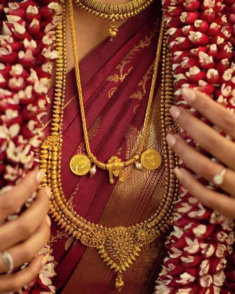 A Woman Wearing A Red And Gold Sari With Two Necklaces On Her Neck