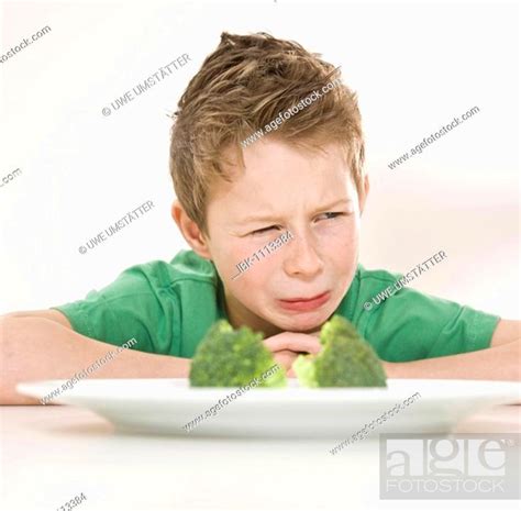 Boy Sitting In Front Of A Plate Of Broccoli With A Disgusted Look On