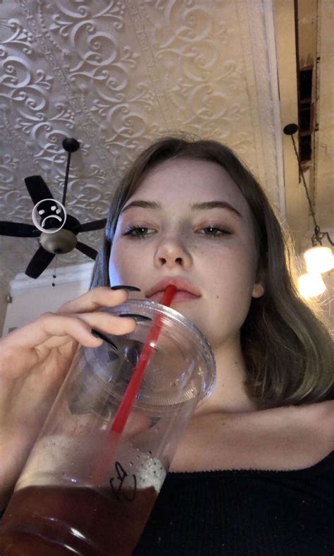 A Woman Drinking From A Cup With A Straw In Her Mouth
