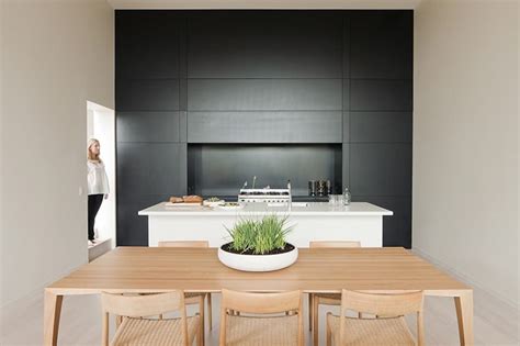 Black and white kitchen features white flat front cabinets adorned with long aged brass pulls paired with soapstone countertops and a light gray grid backsplash. Contemporary Kitchen Cabinets That Redefine Modern Cook Room