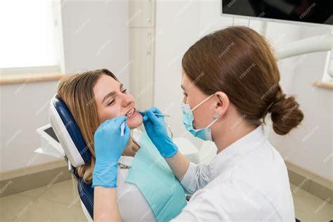 O Dentista Verifica Os Dentes De Um Jovem Paciente Sentado Em Uma