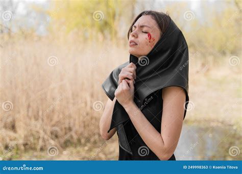Young Widow In A Black Mourning Dress And Headscarf Suffering Praying