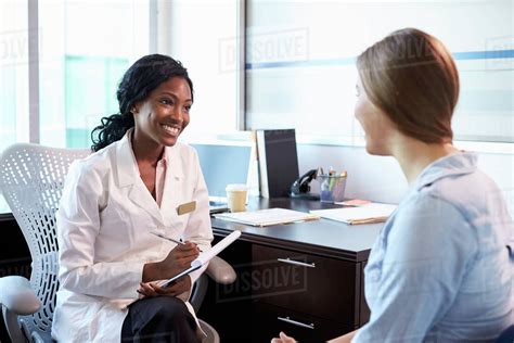Doctor In Consultation With Female Patient In Office Stock Photo
