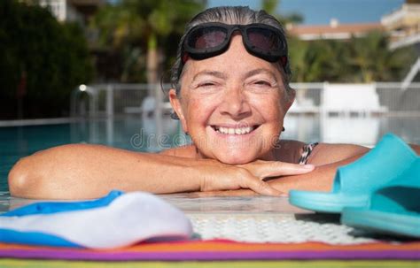 a moment of breath for the attractive senior woman who loves to swim large smile outdoor pool