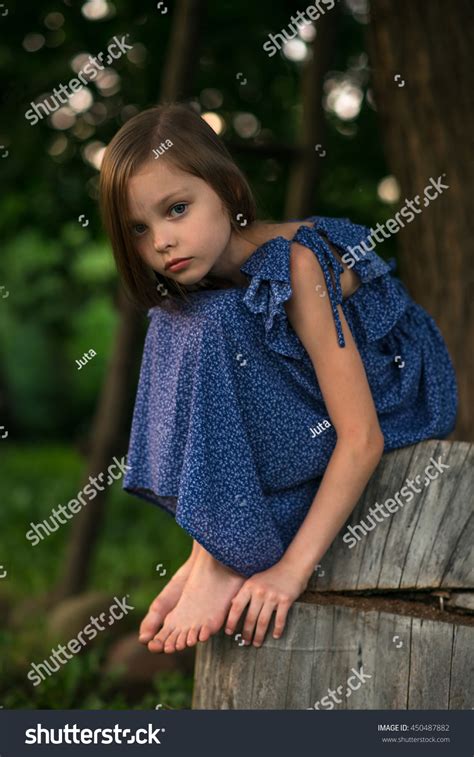Little Sad Girl Sitting Alone Outdoors Stock Photo